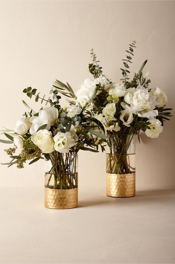 three vases filled with white flowers and greenery