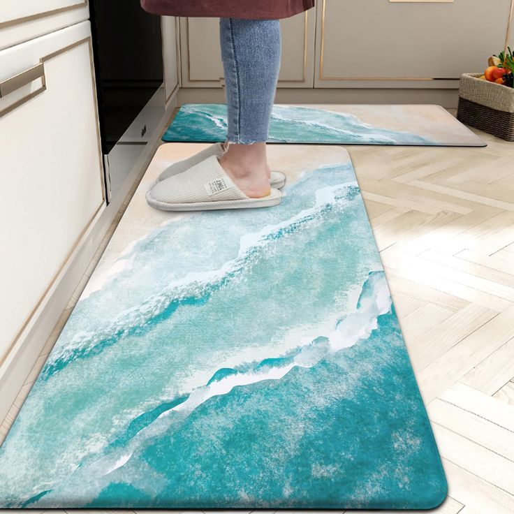 a woman standing on top of a blue rug in a kitchen next to an oven