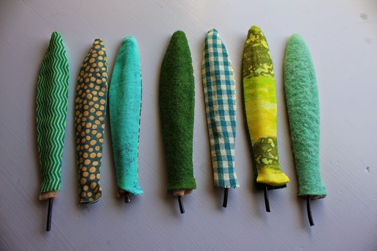 four green and yellow umbrellas are lined up on a table with black metal pins