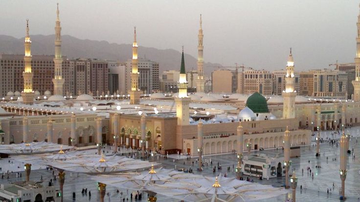 an aerial view of the grand mosque and surrounding buildings at dusk, with people walking around