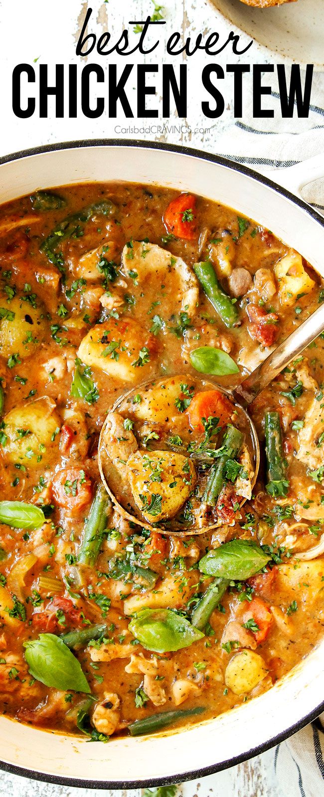 the best ever chicken stew in a white bowl with spoons and bread on the side