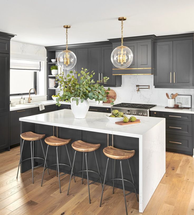 a kitchen with black cabinets and white counter tops, two pendant lights over the island