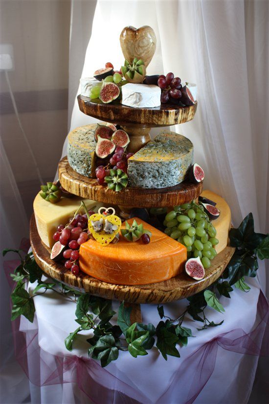 a three tiered platter filled with cheese and grapes