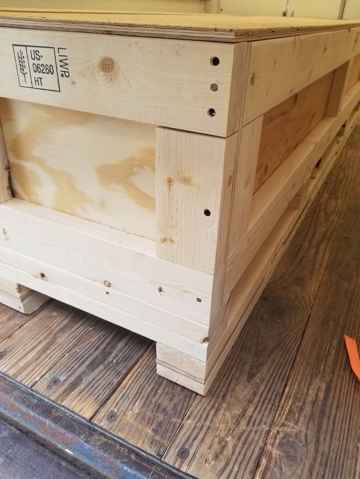 a wooden crate sitting on top of a hard wood floor next to a orange object