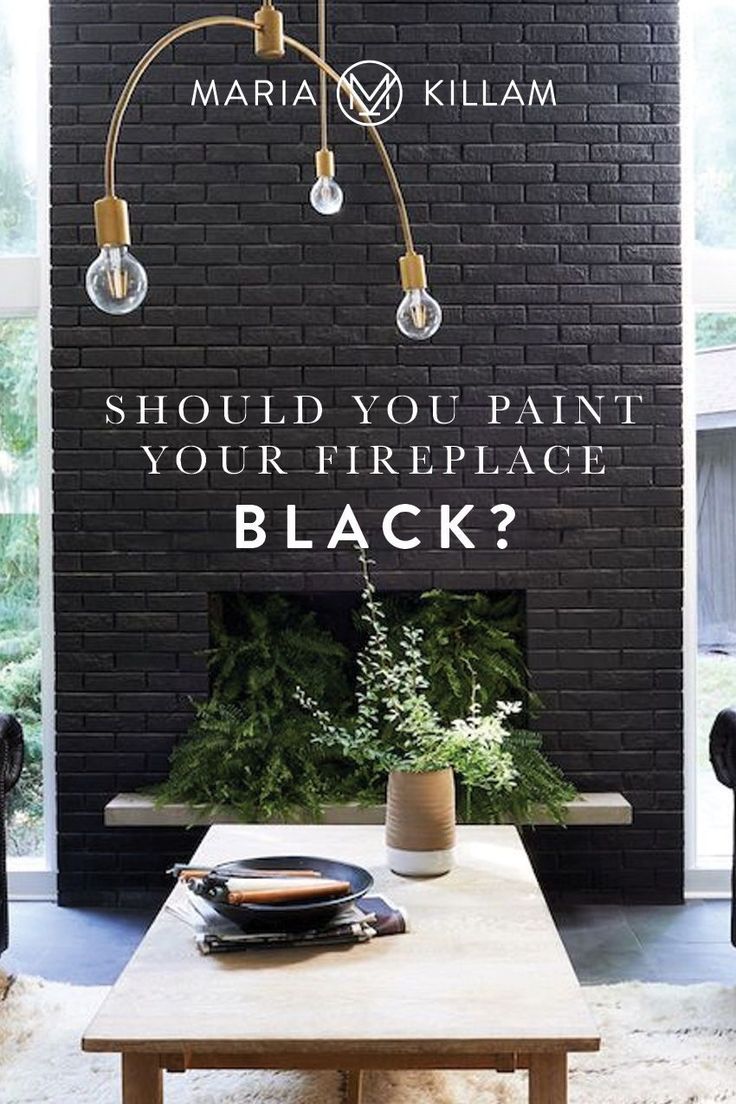 a living room with black brick walls and white carpeted flooring that says should you paint your fireplace black?