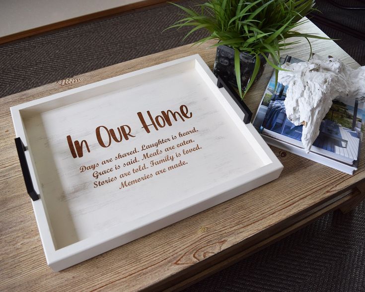 a wooden tray sitting on top of a table next to a potted plant and photos