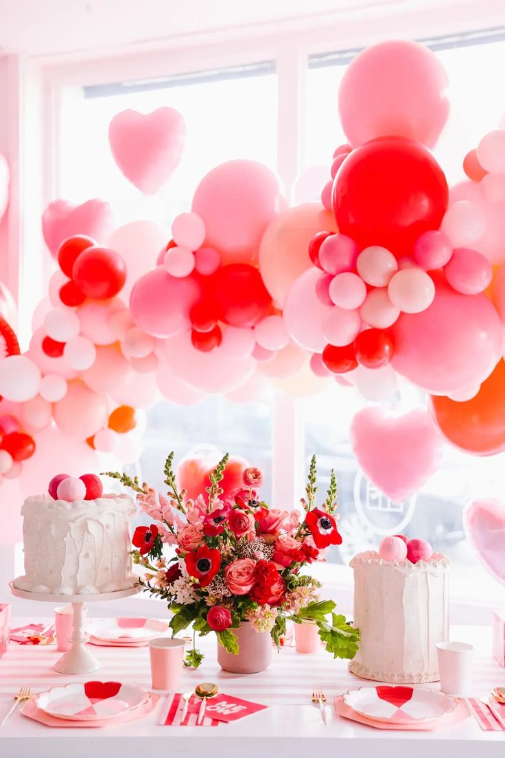 a table topped with lots of pink and red balloons