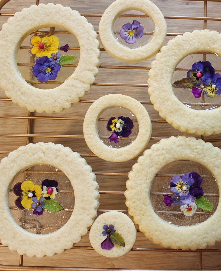 four cookies decorated with edible flowers are sitting on a cooling rack, ready to be baked