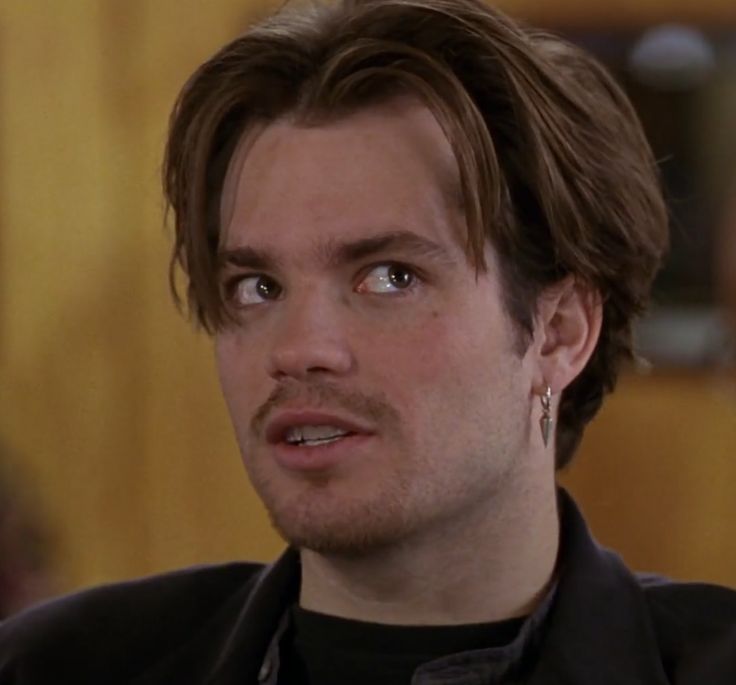 a close up of a person with a serious look on his face and wearing earrings