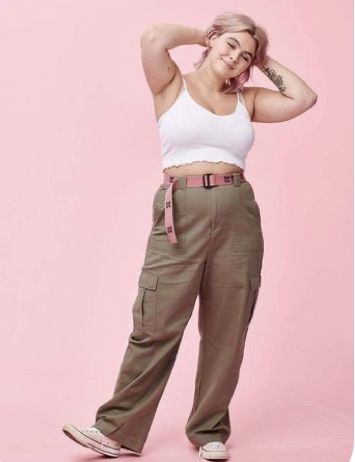 a woman in white shirt and khaki pants posing for the camera with her hand on her head