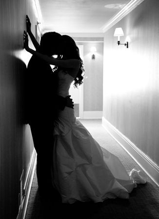 a bride and groom are kissing in the hallway at their wedding reception, black and white photograph