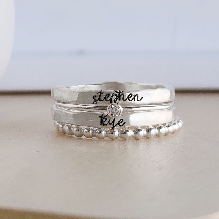 Mother's Day Gift | Personalized stackable ring set, engraved with a name, date, or special word.  Metal: 14k gold filled, 14k rose gold filled, or .999 fine silver Dimensions: name rings are 2mm tall on average, but our rings are handmade so variations will occur. Birthstone is 2mm on a 1mm band and beaded ring is 2mm. Font: lowercase typewriter or lowercase cursive If you leave one name, we will put a heart on the second ring unless you request that it remains blanks. If you have 3 or 4 names, Custom Name Adjustable Stackable Wedding Rings, Adjustable Stackable Rings With Engraving Option For Wedding, Adjustable Stackable Wedding Rings With Engraving, Personalized Sterling Silver Stackable Rings For Anniversary, Personalized Sterling Silver Rings For Mother's Day, Customizable Sterling Silver Stackable Rings As Gift, Customizable Sterling Silver Stackable Rings For Gifts, Hand Stamped Adjustable Stackable Wedding Rings, Stackable Sterling Silver Rings For Personalized Gift