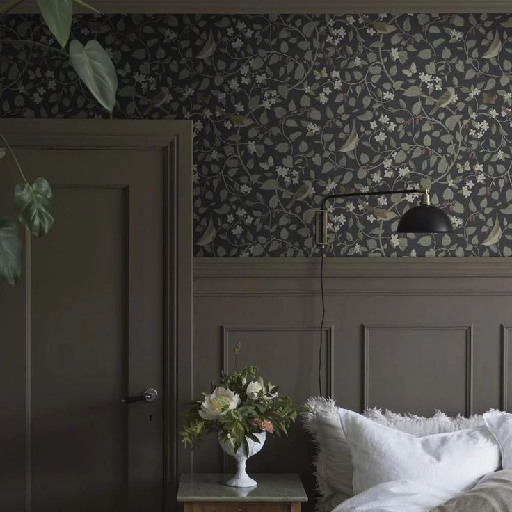 a bedroom with wallpaper and a lamp on the side table in front of it