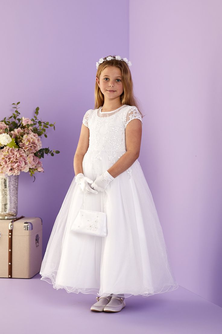 Ruth Shimmer Net Holy Communion Dress A cap sleeved, embroidered lace bodice dress with a sheer neckline and lace overlay at the waist. To finish the skirt has a full shimmer net with a fluted hem The dress is fastened with decorative fabric covered buttons and a hidden zip at the back and is fully lined for maximum comfort. Available in White Shown with the Evelyn Bag, Naomi Glove and Audrey Head Ring DETAILS. Material: Outer: 100% Polyester Lining: 100% Polyester Washing guide: Machine washable Neckline: Round neck Sleeves: Cap sleeves Short Sleeve Lace Dress With Sheer Bodice, Lace Dresses With Illusion Neckline And Short Sleeves, Lace Dress With Illusion Neckline And Short Sleeves, Short Sleeve Lace Dress With Sheer Sleeves, Short Sleeve Dresses With Lace Bodice, Short Sleeve Dress With Fitted Bodice For Confirmation, Cap Sleeve Dress With Lace Bodice, Short Sleeve Tulle Dress With Lace Trim, Short Sleeve Lace Dress With Fitted Bodice