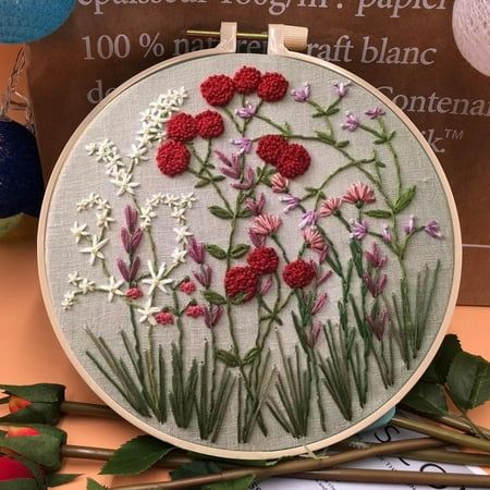 a close up of a embroidery on a table with scissors and flowers in the background