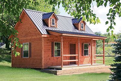 a small log cabin sits in the grass