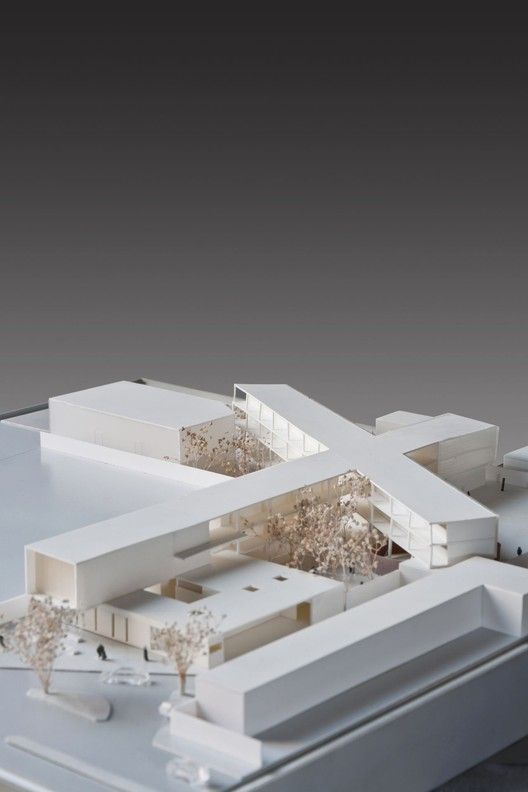 an architectural model of a house on top of a white surface with trees in the foreground