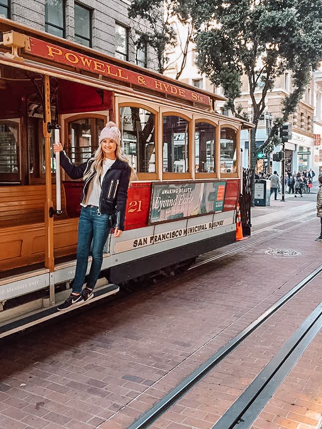 a woman standing on the side of a trolley car