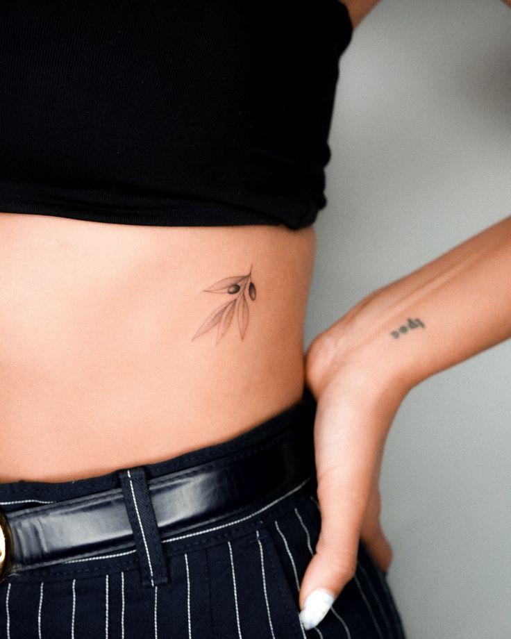 a close up of a person's stomach with a tattoo on her left side