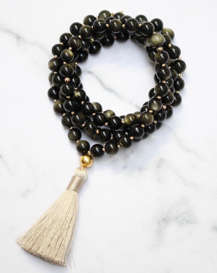 'I am empowered to pursue my passions.' Gold Sheen Obsidian, also known as the "wizard stone," has a long history of being used as a scrying mirror for divination and future prediction. Its reflective surface helps to bring clarity to the mind and alleviate confusion, allowing for deep introspection and personal growth. The reflective nature of Gold Sheen Obsidian has made it a popular tool for self-reflective meditation and fostering internal growth and understanding. Its properties also promot Mystical Jewelry With Natural Stones For Meditation, Mystical Natural Stones Jewelry For Meditation, Mystical Gemstone Beads Jewelry For Meditation, Spiritual Black Necklace For Blessing, Black Spiritual Necklace For Blessing, Spiritual Black Necklace, Spiritual Onyx Jewelry With Gemstone Beads, Spiritual Obsidian Jewelry For Meditation, Healing Onyx Jewelry With 108 Beads