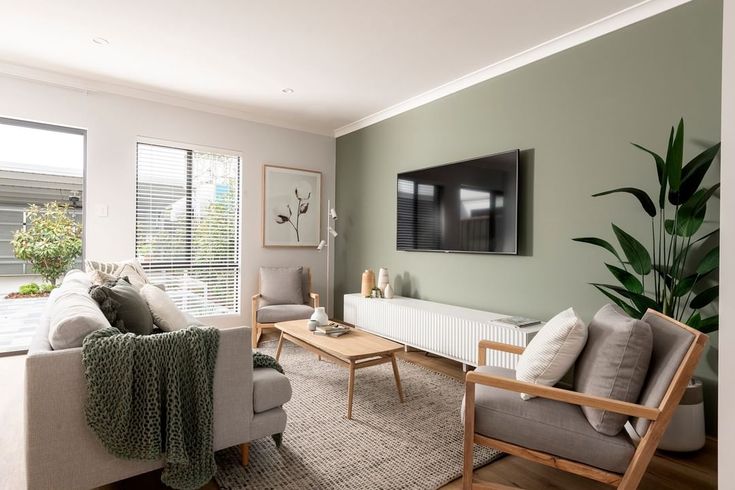 a living room filled with furniture and a flat screen tv mounted on the wall above it