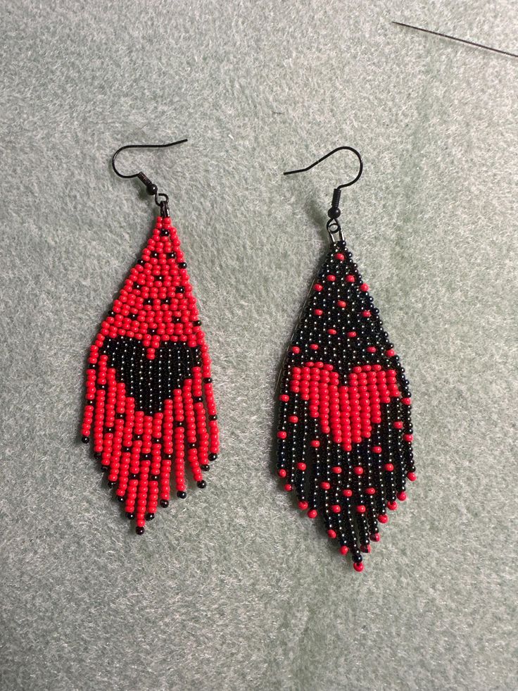 two pairs of red and black beaded earrings sitting on top of a gray surface