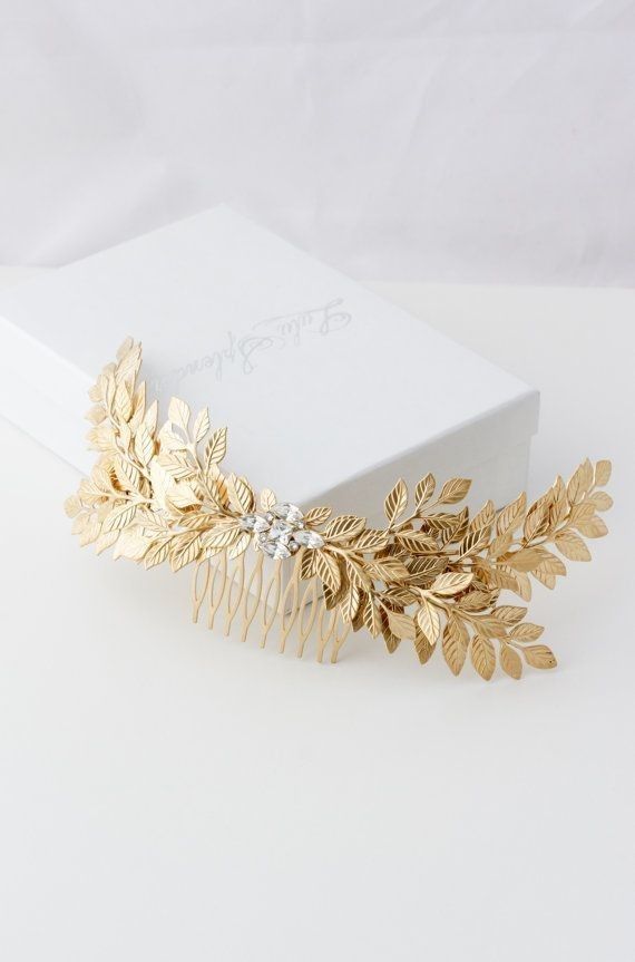 a gold hair comb with leaves and crystals on it's headband, sitting in front of a white box