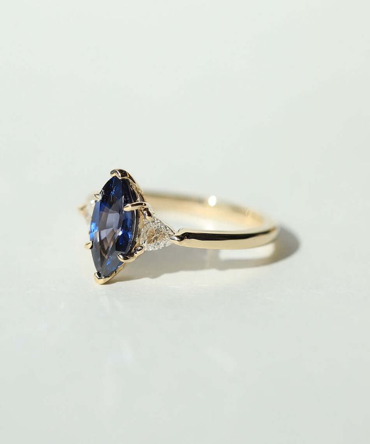 A marquise shaped blue sapphire, with diamond trillions set in 14k yellow gold Specifications: 1.3ct dark blue sapphire 10mm tall, approx 0.3ct trillion diamonds in recycled 14k gold. Please note each sapphire is one of a kind and textures vary Custom sized in approx. 10-14 days. Please contact us about rush orders. Please contact us about our stock availability other metal colors and sizes not listed at shop@machastudio.com Women's Wedding Bands, Trillion Diamonds, Diamond Huggies, Traditional Engagement Rings, Paper Ring, Diamond Drops, Emerald Engagement Ring, Womens Wedding Bands, Engagement Jewelry