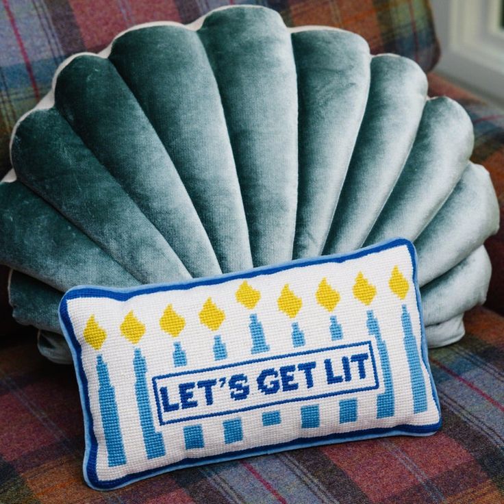 a pillow that says let's get lit on the back of a chair with a shell cushion