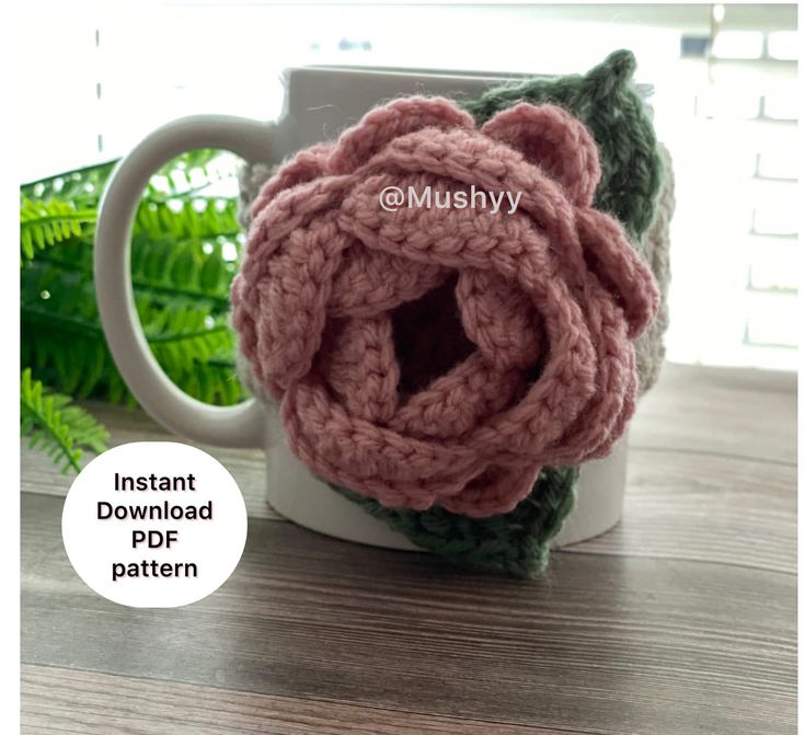 a crocheted flower sits on top of a coffee mug