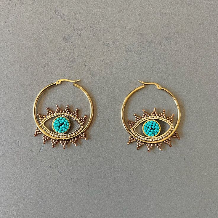 Evileye protection hoop earrings beads hoop earrings Miyuki earrings Miyuki bead earrings evil eye shape earrings bohemian earrings everyday Add a unique style to any look with these bohemian style earrings featuring an evil eye. Constructed with Miyuki seed beads in a combination of aqua and gold seed beads, they are sure to catch any eye with their stunning design. Lightweight and comfortable. Item Details *Material: Stainless Steel *Stone: Glass seed beads *Earring size: 1.57in (4cm) *Weight: Miyuki Earrings, Aqua And Gold, Miyuki Bead, Earrings Beads, Earrings Everyday, Earrings Bohemian, Eye Shape, Miyuki Beads, Beaded Hoop Earrings