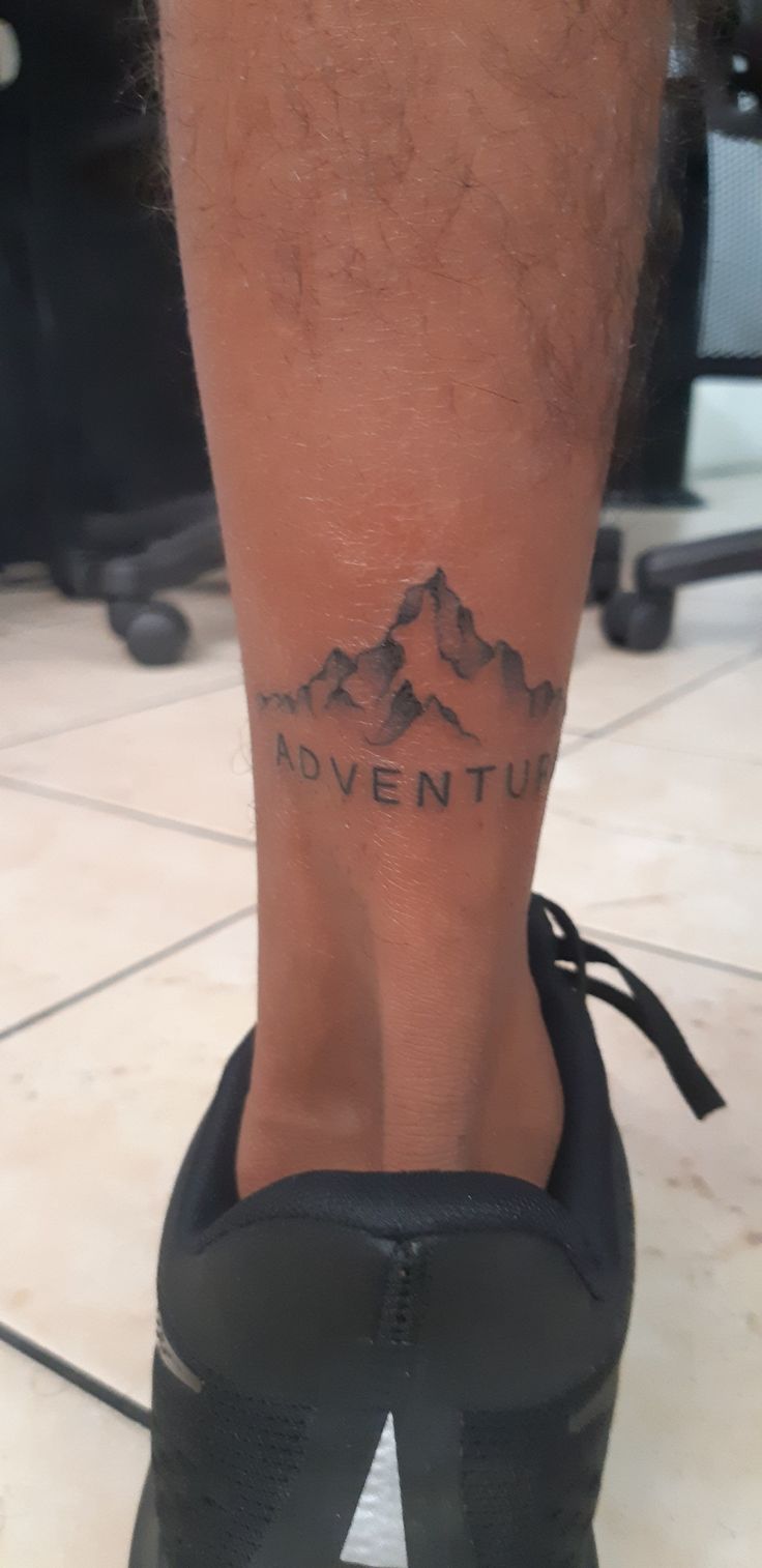 a man's foot with a tattoo that reads adventure on the side of his leg