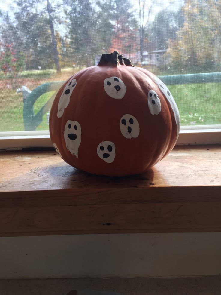 a pumpkin sitting on top of a window sill with ghost eyes painted on it