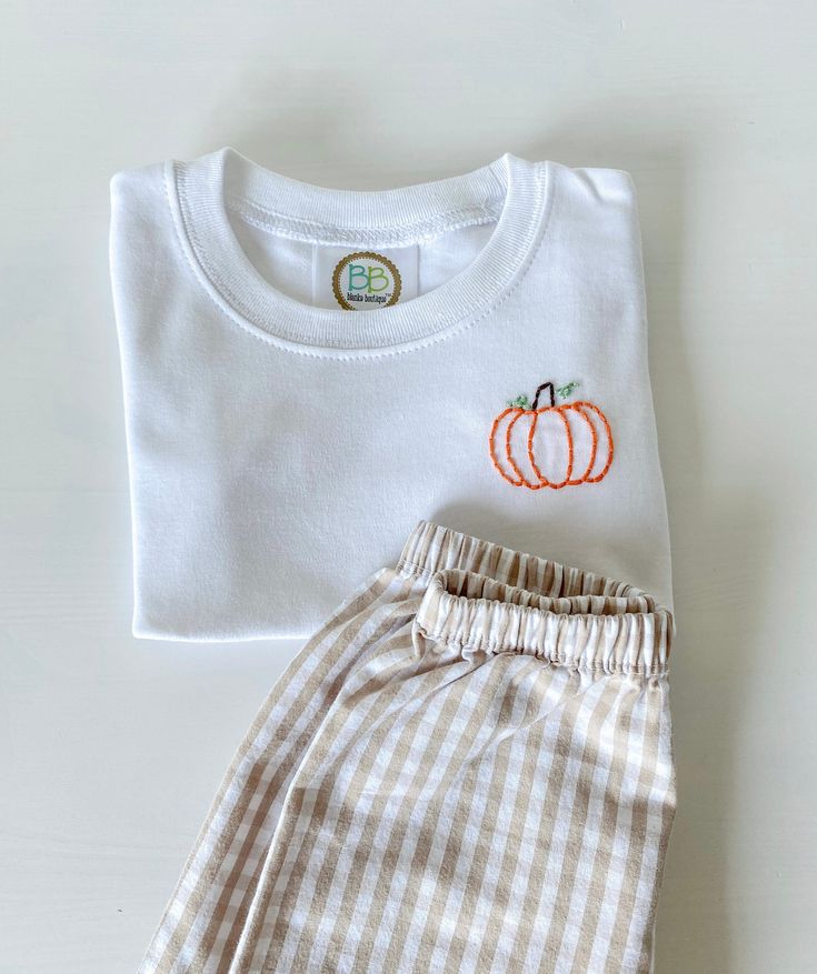 Hand embroidered pumpkin t shirt! If you need your item quicker please message and I'll be happy to accommodate! Follow my Instagram for more! stitchedxalicia Smiley Face Embroidery Design, Embroidered Halloween Shirts, Hand Embroidered Pumpkin, Newborn Embroidery Clothes, Hand Embroidery Pumpkin, White T-shirt With Custom Embroidery For Fall, Custom Embroidered White T-shirt For Fall, White Custom Embroidered T-shirt For Fall, Embroidered White T-shirt For Fall