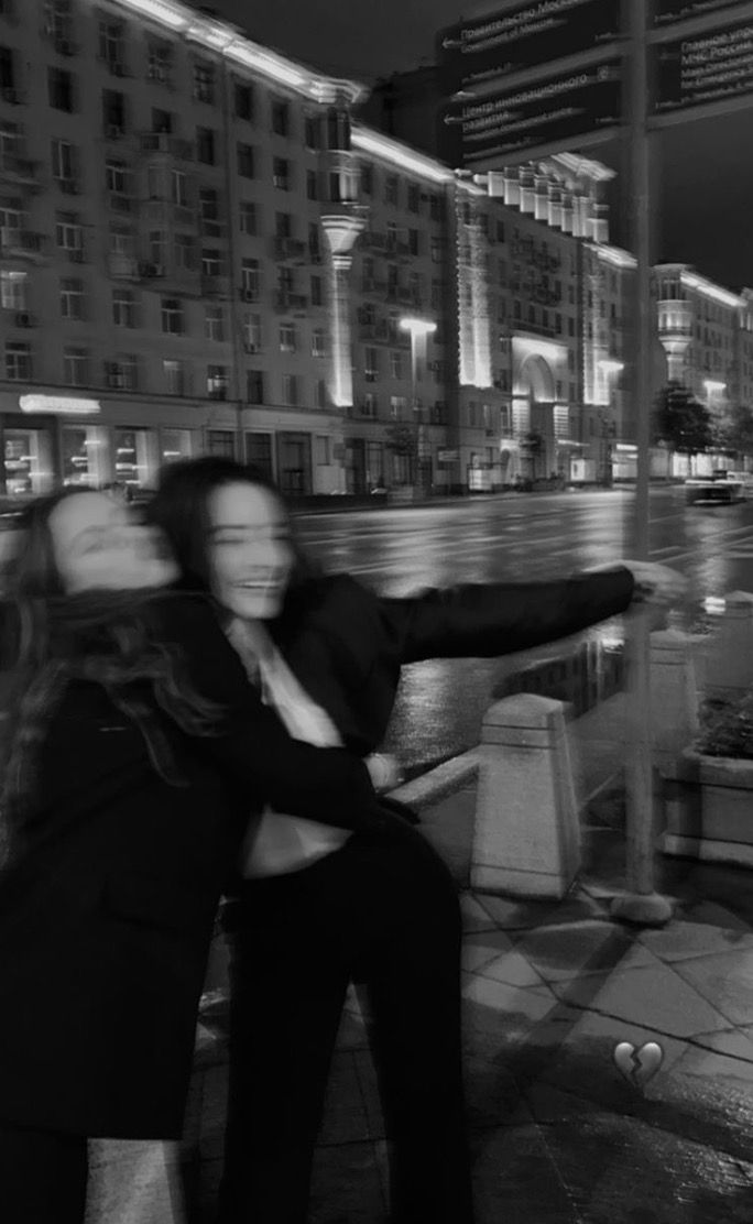 black and white photograph of two people hugging in front of a city street at night