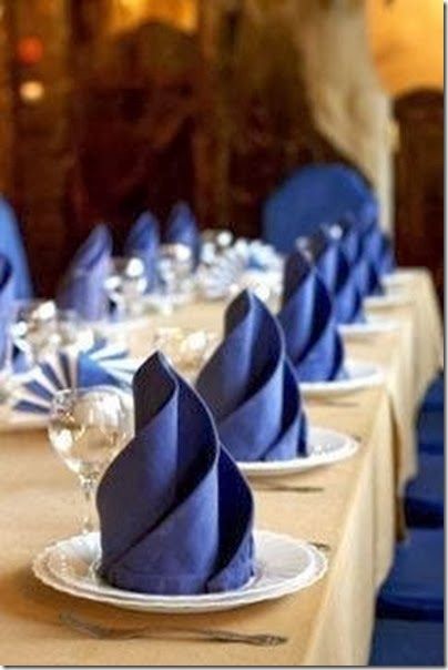 the table is set with blue napkins and wine glasses