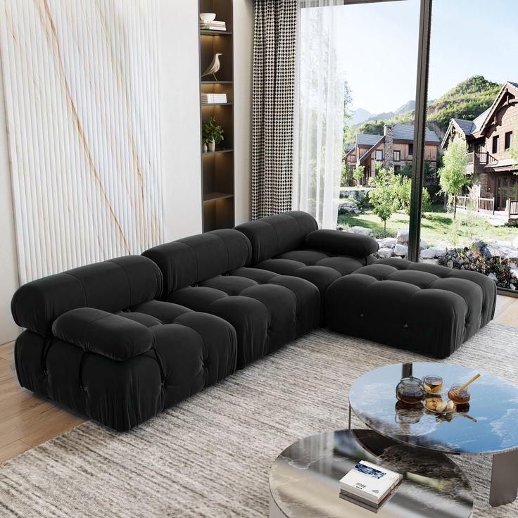 a large black couch sitting in front of a glass table on top of a rug