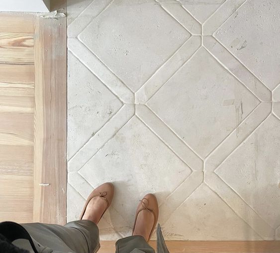 a person standing on the floor with their feet up in front of a tile wall