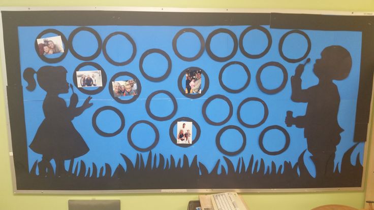 a bulletin board with children's silhouettes and circles on it in front of a computer desk