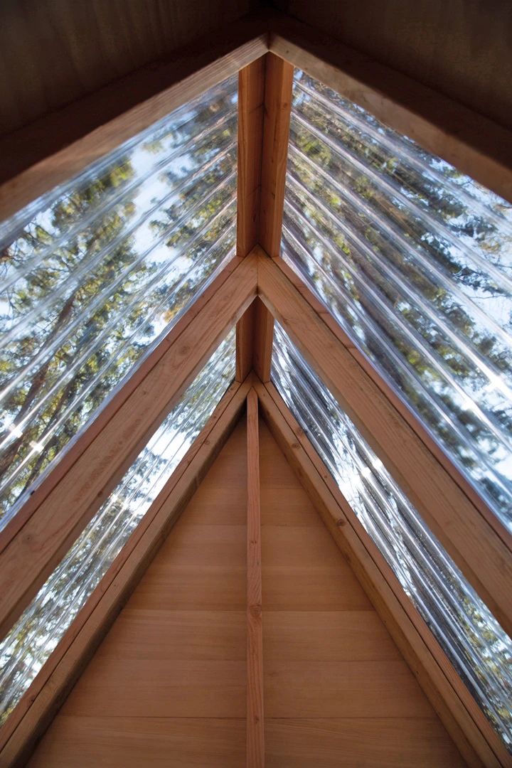 the inside of a building with wood and glass on the roof, looking up at the sky