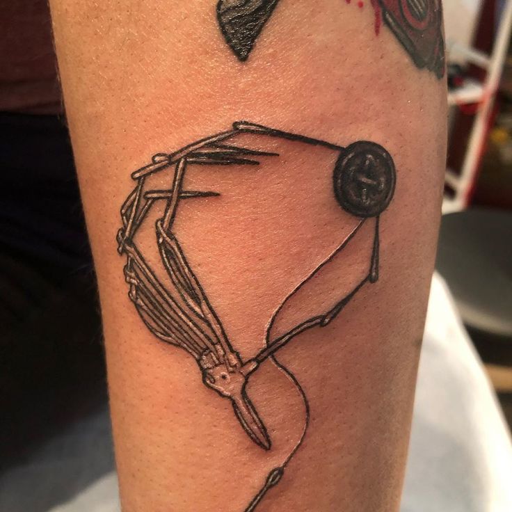 a tattoo on the arm of a woman with scissors and thread in it, which is drawn