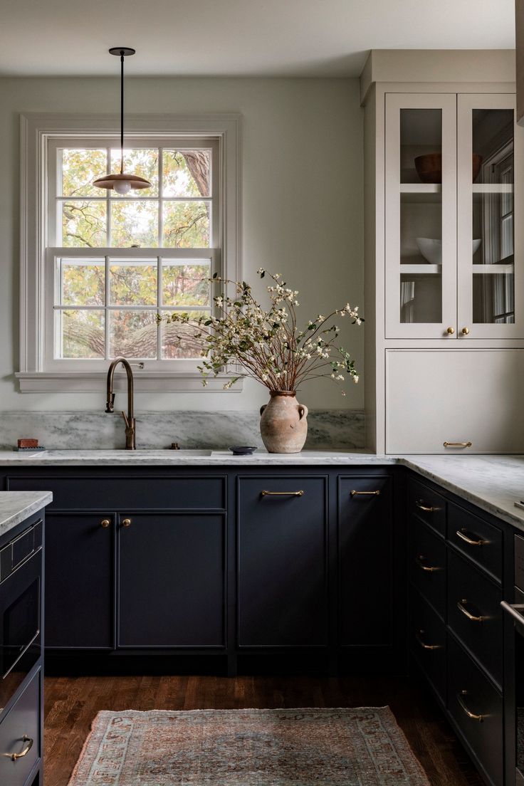 a kitchen with dark blue cabinets and white counter tops, an area rug on the floor