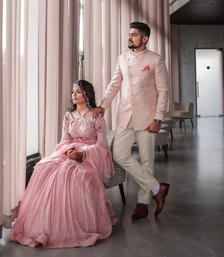 a man in a pink suit and woman in a pink dress sitting on a chair