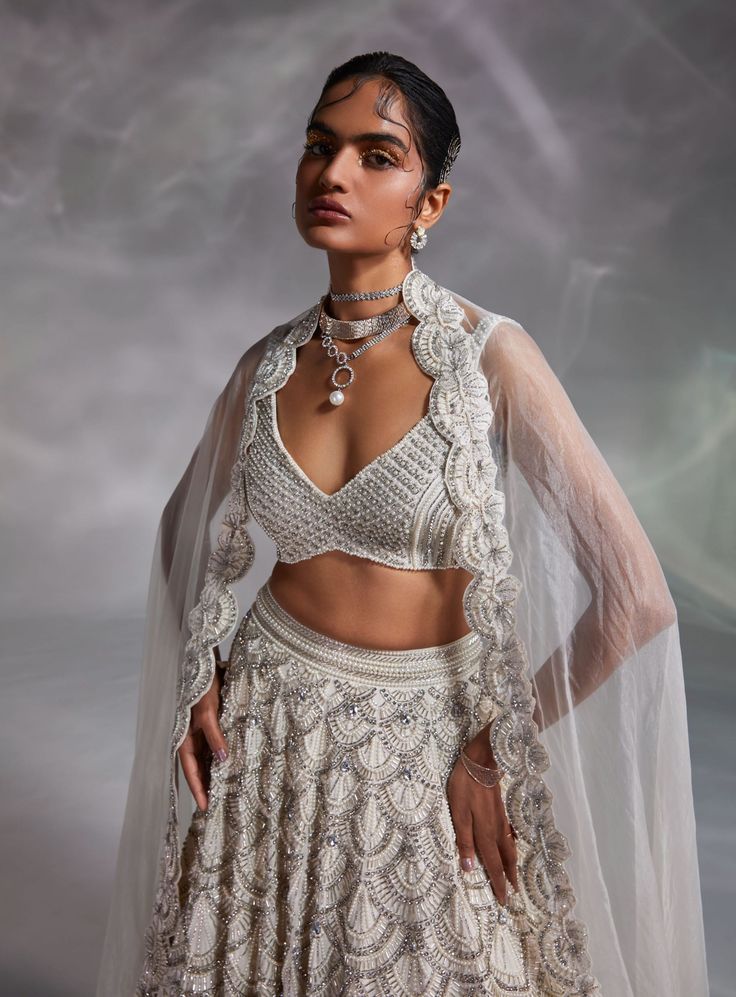 Editor's Note Featuring an off-white hand-embellished blouse, lehenga and solid dupatta with embroidered border Color: Off-white Fabric: Crushed organza, silk and organza Fit type: Blouse: fitted Neckline: V-neckline Components: Lehenga, blouse and dupatta Occasion: Wedding Care: Dry Clean Only About the Designer The crux and essence of the label, Divya Aggarwal, is to challenge and revamp the face of ordinary traditional wear while being customer oriented. Driven by the values of individuality Lehenga Silk, Off White Blouse, Blouse Yoke, Raw Silk Lehenga, Embellished Blouse, Silk Lehenga, Embroidered Jacket, White Silk, Sheer Sleeves