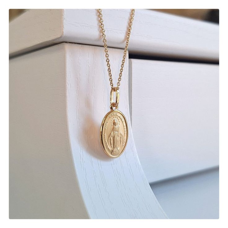 This beutiful oval shaped Miraculous Medal is made with 18 kt gold plating sterling silver. Medal is satin texture with diamond cut edges. Technique of making this medal is minting ( coining ) so it is very detailed. Item deatils:  Dimensions of medal is 25 mm or  (0'98 inch) x 11 mm(0,48 inch).  Weight of medal: 1, 8 gr. Available necklace lengths: 42 cm (16, 5 inch), 50 cm (19,7 inch) and 60 cm ( 23,6 inch). This size of medal is ideal for teenage girls or women that prefers miniature Miraculo Yellow Gold Oval Pendant For Anniversary, Spiritual Oval Miraculous Medal Jewelry And Charms, Spiritual Oval Miraculous Medal Jewelry, Gold Engraved Oval Cabochon Necklace, Spiritual Oval Jewelry For Commemoration, Oval Spiritual Jewelry For Commemoration, Gold Oval Pendant Spiritual Jewelry, Yellow Gold Jewelry With Oval Pendant For Commemoration, Oval Miraculous Medal Spiritual Jewelry