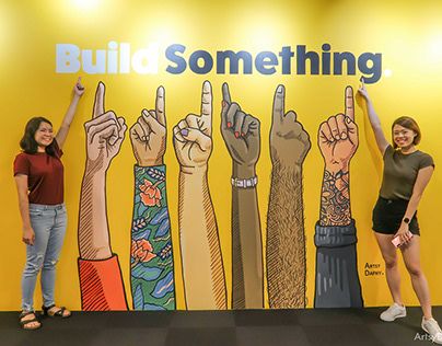 two women are standing in front of a wall that says build something with their hands