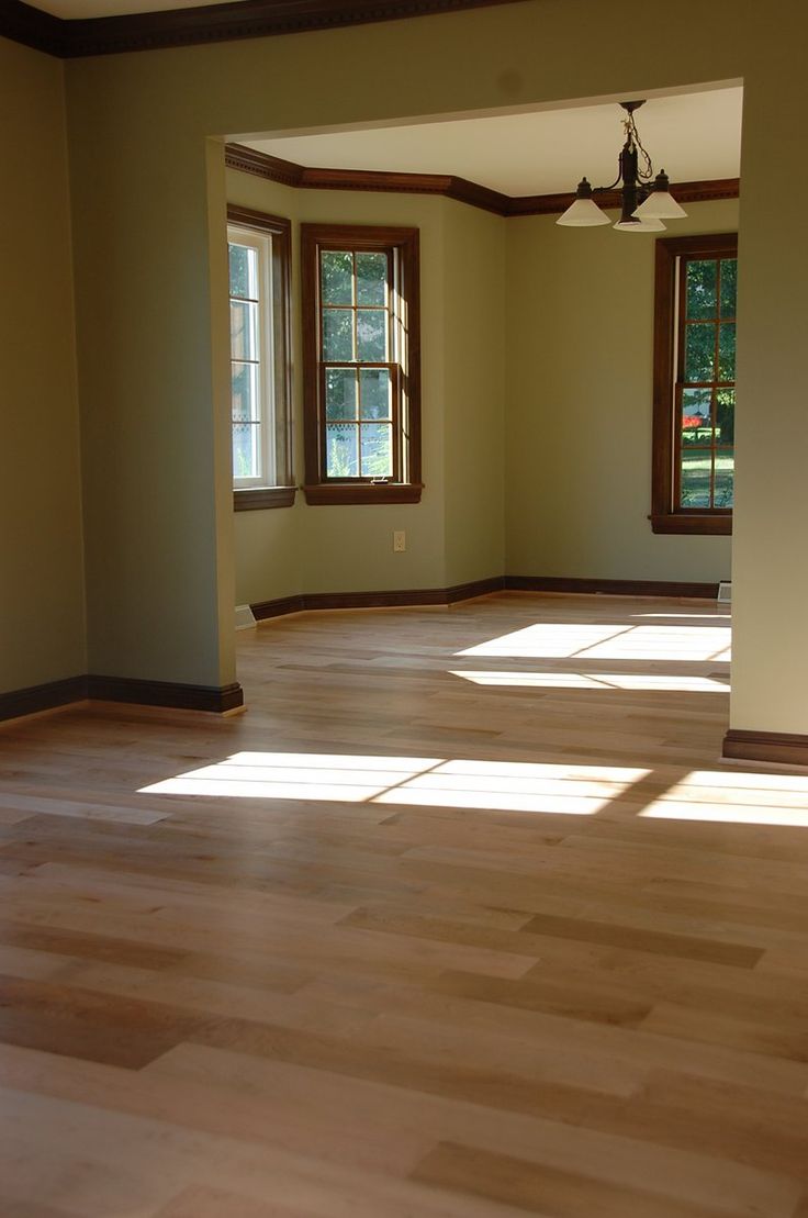 an empty room with hard wood floors and windows