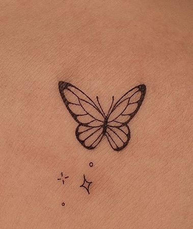 a small butterfly tattoo on the back of a woman's stomach, with stars around it