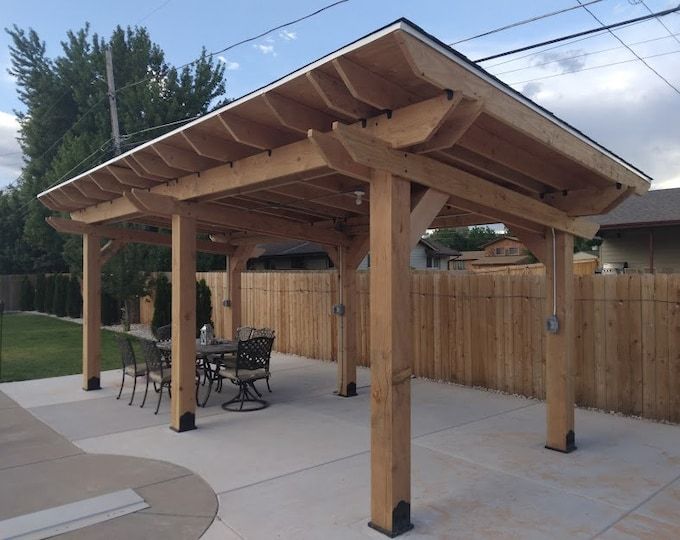 an outdoor covered patio with tables and chairs next to a fenced in backyard area