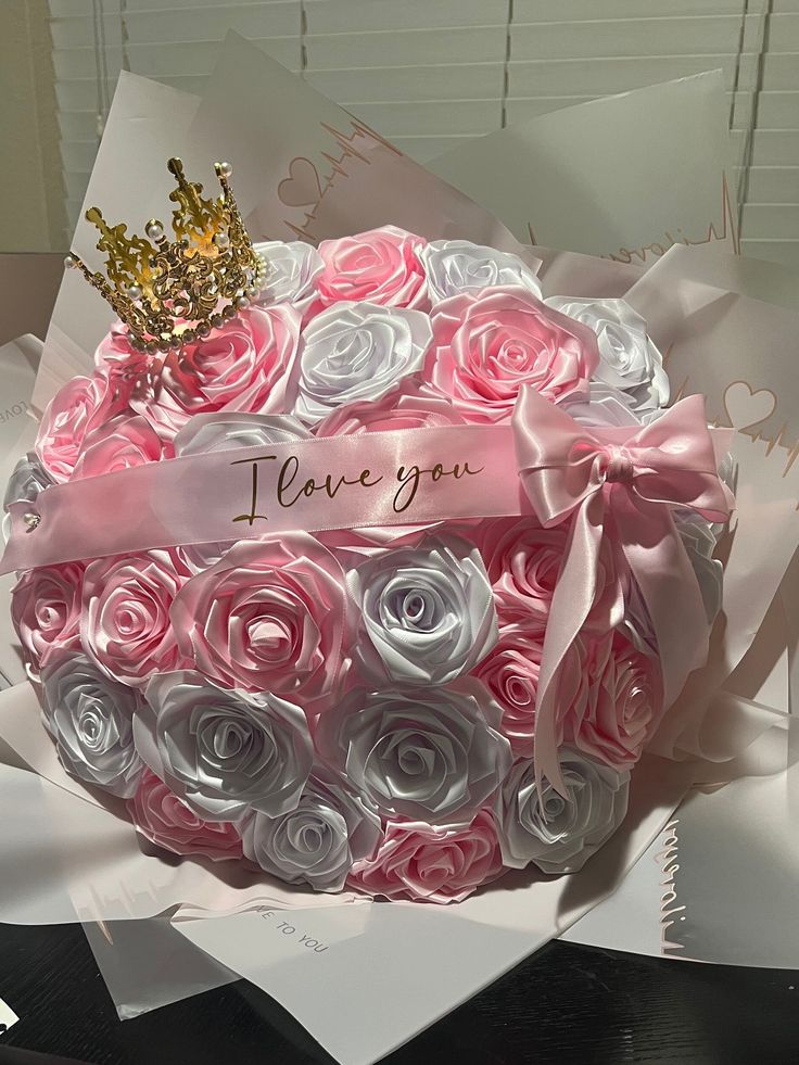 a large pink and white rose bouquet with a gold crown on top that says i love you